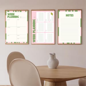 Op de afbeelding: Drie ingelijste wandkunstwerken met een roze en groen kleurenschema. Het linker frame zegt "WEEK PLANNING" en heeft een wekelijkse planner layout. Het middelste frame zegt ook "WEEK PLANNING" en heeft een dagelijkse planner layout. Het rechter frame zegt "NOTES" en heeft gelijnd papier.