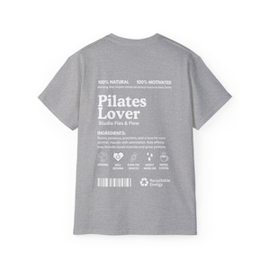 Puede incluir: Una camiseta gris jaspeado con la frase "Pilates Lover" en blanco y el texto "Studio Flex & Flow". La camiseta tambi&eacute;n presenta texto sobre ingredientes e iconos relacionados con el pilates.