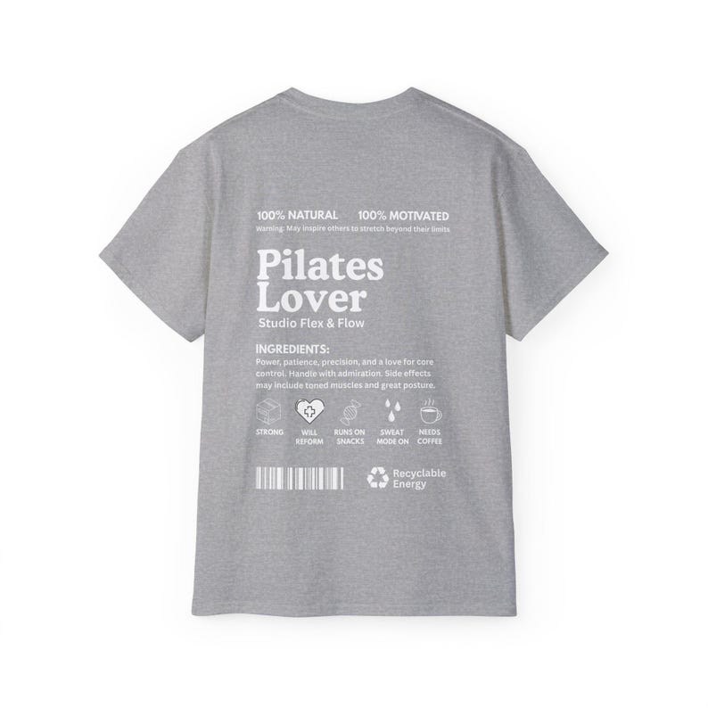 Puede incluir: Una camiseta gris jaspeado con la frase "Pilates Lover" en blanco y el texto "Studio Flex & Flow". La camiseta tambi&eacute;n presenta texto sobre ingredientes e iconos relacionados con el pilates.