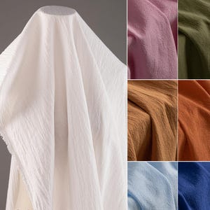 May include: A collection of eight fabric swatches in various colors, including white, pink, green, brown, light blue, and dark blue. The fabric has a textured, crinkled look.