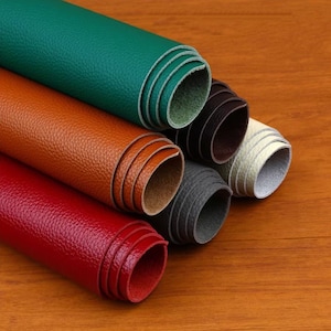 May include: A collection of six rolls of leather in various colors, including green, brown, red, black, and white. The leather is textured and appears to be of high quality.