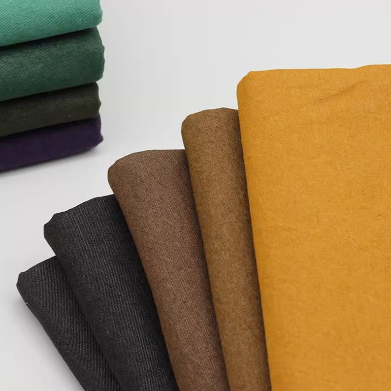 May include: A stack of fabric swatches in various colours, including green, brown, black, and yellow. The swatches are folded and arranged in a fan shape.