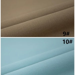 Pu&ograve; includere: Due campioni di tessuto, uno beige e uno azzurro chiaro, con una trama testurizzata. I campioni sono etichettati "9#" e "10#" rispettivamente.
