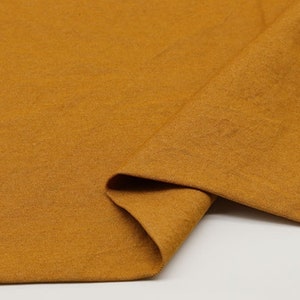 May include: A close-up of a folded piece of mustard yellow fabric. The fabric has a soft, textured surface. The number "5#" is written in white on the fabric.