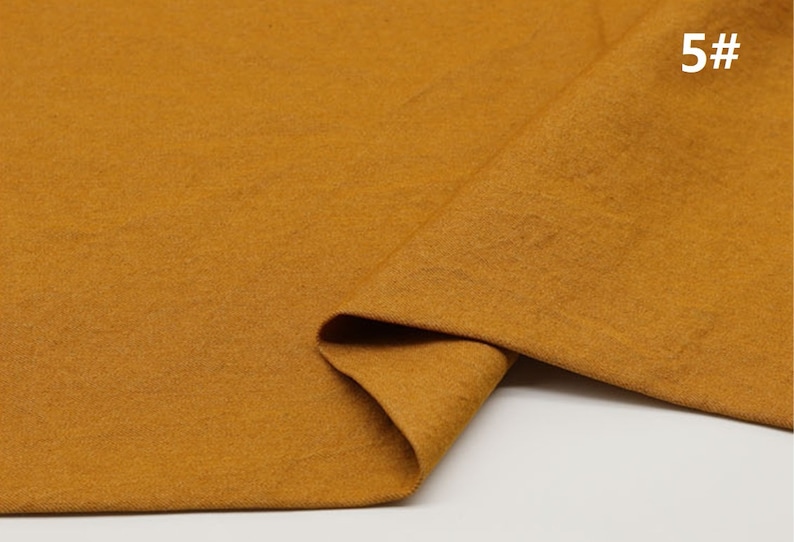 May include: A close-up of a folded piece of mustard yellow fabric. The fabric has a soft, textured surface. The number "5#" is written in white on the fabric.