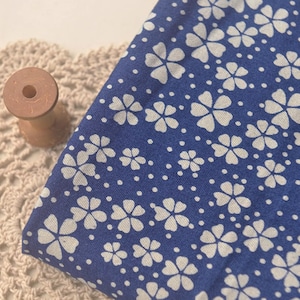 May include: Blue fabric with a white floral pattern and white polka dots.