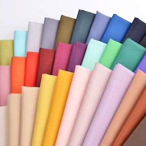 May include: A collection of fabric swatches in various colors, including green, blue, purple, red, orange, yellow, and brown. The swatches are arranged in a fan shape, with the darkest colors at the bottom and the lightest colors at the top.