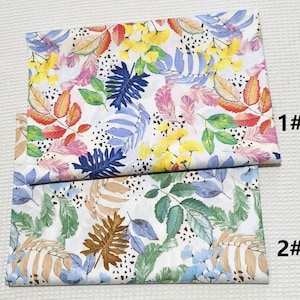 Może przedstawiać: Dwa próbniki tkaniny z różnymi wzorami kwiatowymi. Górny próbnik ma białe tło z różowymi, niebieskimi, żółtymi i czerwonymi akwarelowymi liśćmi i kwiatami. Dolny próbnik ma białe tło z zielonymi, niebieskimi i brązowymi akwarelowymi liśćmi i kwiatami. Próbniki są oznaczone odpowiednio "1#" i "2#"