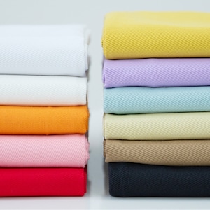 Pu&ograve; includere: Un assortimento di campioni di tessuto in vari colori, tra cui bianco, arancione, rosa, rosso, beige, azzurro, lavanda e giallo. Il tessuto ha una texture sottile ed &egrave; piegato con cura.