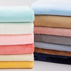 Puede incluir: Una pila de mantas de felpa en varios colores pastel, incluyendo azul claro, blanco, rosa, coral, amarillo, beige, gris y azul marino. Las mantas están cuidadosamente dobladas, mostrando su suave textura y tonos vibrantes. Ideal para decoración del hogar.