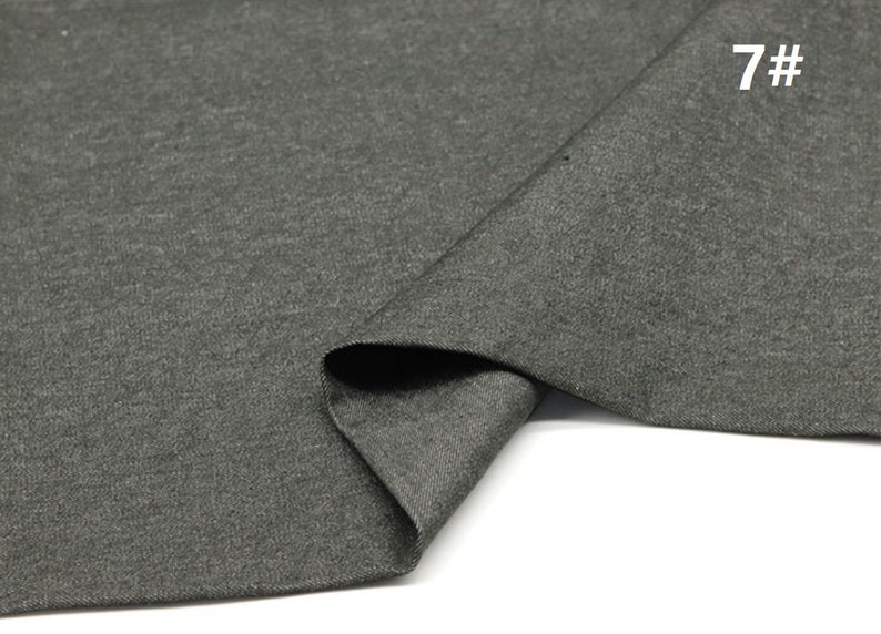May include: A close-up of a dark grey fabric with a textured surface. The fabric is folded in half and the edges are visible. The number "7#" is printed in white on the fabric.