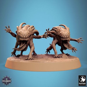 May include: Two brown monster figurines with sharp teeth and clawed hands are posed on a tan base. The monsters have large heads with horn-like protrusions and are set against a blue background. The text "Fate Unbound" is visible.