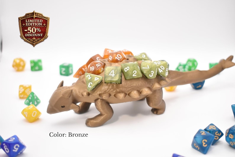 K&ouml;nnte beinhalten: Bronze-farbener W&uuml;rfelhalter in Dinosaurierform mit orangefarbenen und gr&uuml;nen W&uuml;rfeln. Der Halter ist als Ankylosaurus gestaltet. Das Bild enth&auml;lt auch ein "Limited Edition -50% Discount"-Abzeichen.