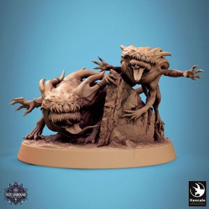 Puede incluir: Escultura de fantasía marrón detallada de dos criaturas grotescas con dientes afilados y extremidades extendidas. Una criatura está posada sobre una formación rocosa, la otra en el suelo. La base es de color marrón claro. La imagen tiene el texto "Fate Unbound" y "Rescale".