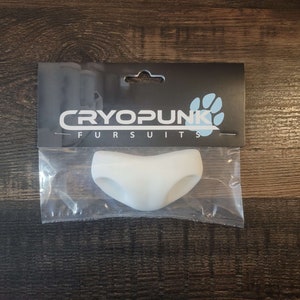 May include: White, flexible, silicone tail piece for a furry costume. The tail piece is shaped like a V and has two small holes on the sides. The packaging has the text "Cryopunk Fursuits".