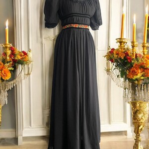 May include: A black maxi dress with a lace neckline and short puff sleeves. The dress has a velvet waistband with a floral embroidered trim.