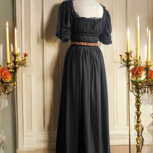 May include: A black maxi dress with a square neckline and short puff sleeves. The dress has a lace trim at the neckline and a floral embroidered belt.