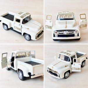 May include: White toy pickup truck with gold lettering that says "Big Brother" and "Ethan". The truck has an open door and bed.