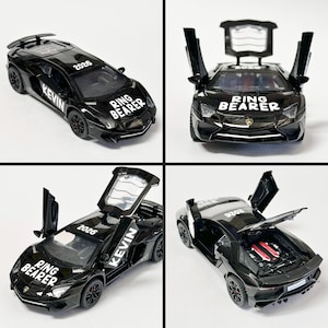 May include: A black toy sports car with the text "RING BEARER" on the front and "KEVIN" on the side. The car's doors and hood are open in some images. The year "2026" is printed on the car.