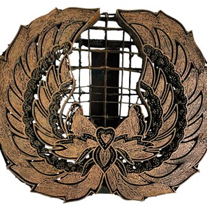 May include: A copper-coloured batik stamp featuring a detailed design of two wings and a heart-shaped flower in the centre.