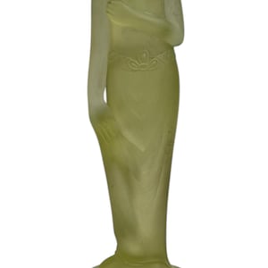 May include: A pale green art deco figurine of a woman, standing on a round base with several holes. The figure is draped in a flowing gown, with one arm raised. The statue is approximately 20 cm tall.