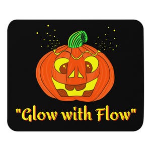 Könnte beinhalten: Ein Halloween-Mauspad mit einem lächelnden Kürbis-Gesicht. Der Kürbis ist orange mit gelben Augen und Zähnen und einem grünen Stiel. Der Text "Glow with Flow" ist in Gelb und Orange. Der Hintergrund ist schwarz.