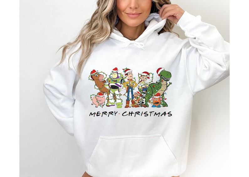 Pu&ograve; includere: Felpa bianca con una grafica natalizia dei personaggi di Toy Story che indossano cappelli di Babbo Natale e sono circondati da luci natalizie. Il testo "Merry Christmas" &egrave; stampato sotto la grafica.