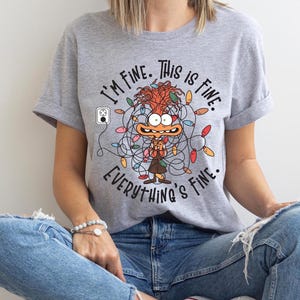 May include: A gray t-shirt with a cartoon character tangled in Christmas lights. The text on the shirt reads "I'm fine. This is fine. Everything's fine."