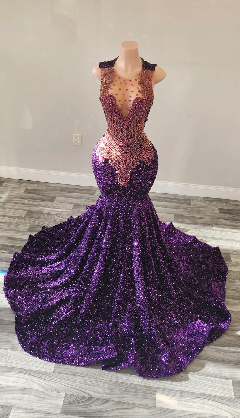 Puede incluir: Un vestido de sirena de lentejuelas moradas con un corpi&ntilde;o de cuentas doradas. El corpi&ntilde;o tiene un escote transparente y un dise&ntilde;o en V pronunciado.