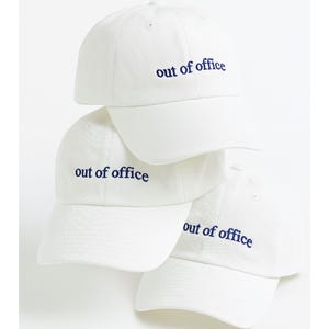 Może przedstawiać: Stos czterech białych czapek z daszkiem. Każda czapka ma zakrzywiony daszek i napis "out of office" wyhaftowany w kolorze granatowym. Casualowy dodatek.