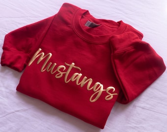 May include: Red sweatshirt with the word "Mustangs" in gold lettering.