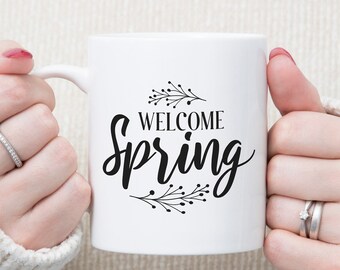 May include: White ceramic mug with black text that reads "Welcome Spring" surrounded by a simple floral design.