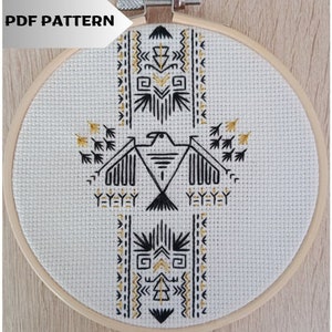 Peut inclure: Un motif de broderie noir et or sur un tissu blanc dans un cercle de broderie en bois rond. Le motif représente un oiseau stylisé avec des motifs géométriques au-dessus et en dessous. Le texte "PDF PATTERN" est visible en haut de l'image.
