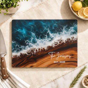 May include: A rectangular cutting board featuring a wood grain pattern on the bottom half and a deep blue ocean wave design with white sea foam on the top half. The board includes the white text The Johnsons and EST. 2026 printed on the surface.