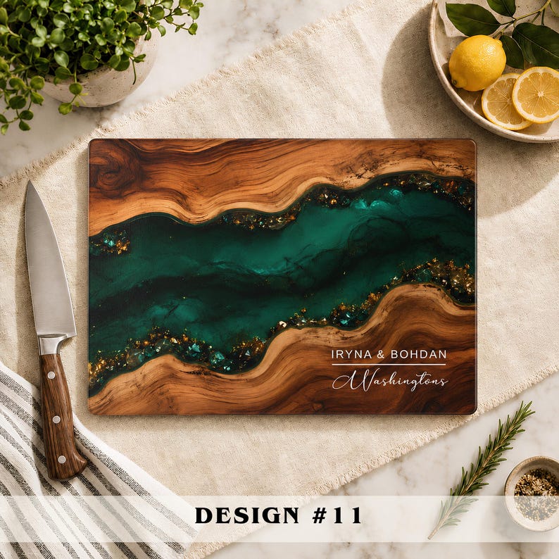 A rectangular wooden cutting board featuring a central river-like inlay of deep emerald green resin with gold flecks. The board is engraved with the text IRYNA & BOHDAN and the script name Washingtons in the lower right corner.