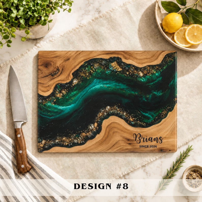 May include: A rectangular wooden cutting board featuring a central river design made of dark green and black resin with embedded gold flakes. The board is engraved with the text Brians SINCE 2026 in a black script and print font.