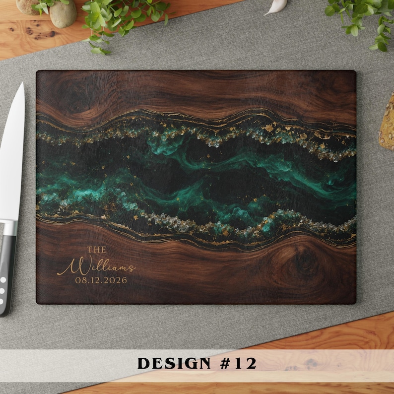 A rectangular wooden cutting board featuring a dark brown wood grain and a central horizontal band of swirling emerald green and black resin with gold flecks. The text THE Williams 08.12.2026 is engraved in the bottom left corner.