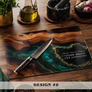 May include: A rectangular glass cutting board featuring a wood grain pattern with a swirling teal and gold resin accent. The board displays the text Home Sweet Home and THE JOHNSONS. A metal kitchen knife with a dark handle rests on the surface.