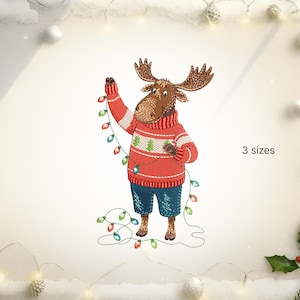 Puede incluir: Diseño bordado de un alce con un suéter rojo con un patrón de árbol verde y pantalones cortos azules, sosteniendo una cadena de luces navideñas de colores. La imagen incluye el texto "3 sizes".