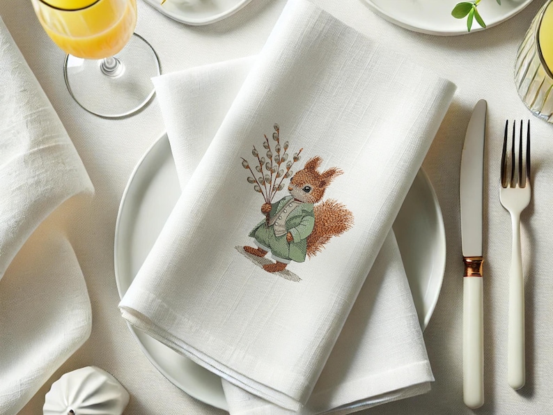 May include: White linen napkin with an embroidered design of a squirrel holding a sprig of willow branches. The squirrel is wearing a green jacket and has a brown tail.