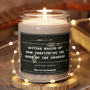 May include: A brown glass candle jar with a black label that reads "Smells Like Getting Railed By Dom Toretto On The Hood Of The Charger". The label also says "Scented Candle" and "Flare for the Dramatic".