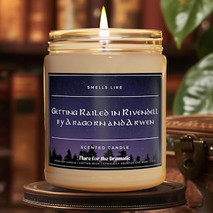 Könnte beinhalten: Eine Sojawachskerze mit einem schwarzen und violetten Etikett, auf dem "Getting Railed in Rivendell by Aragorn and Arwen" steht. Das Etikett trägt außerdem die Aufschrift "Smells Like" und "Scented Candle: Flare for the Dramatic".