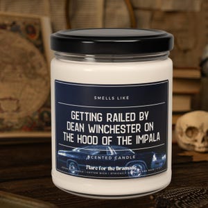 May include: White candle jar with a black lid. The label reads "Smells Like Getting Railed By Dean Winchester On The Hood Of The Impala". The label also has a picture of a car and the text "Scented Candle Flare for the Dramatic".