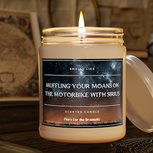 May include: A scented candle with a black label that reads "Smells Like Muffling Your Moans On The Motorbike With Sirius" and "Scented Candle Flare for the Dramatic". The candle is lit and has a starry night sky background.