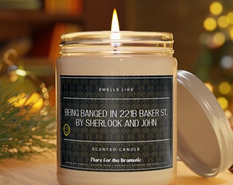 May include: A white scented candle in a glass jar with a black label that reads "Smells Like Being Banged in 221B Baker St. By Sherlock and John". The label also says "Scented Candle" and "Flare for the Dramatic".