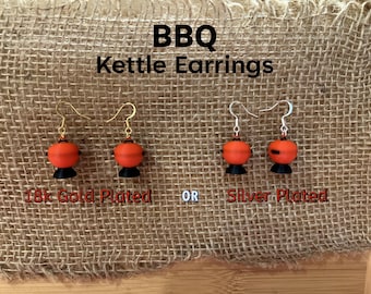 May include: A pair of earrings shaped like a red and black BBQ kettle. The earrings are available in 18k gold plated or silver plated.