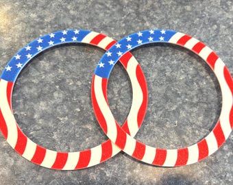 May include: Two circular patriotic decorations with a design inspired by the American flag. Each ring features a blue section with white stars and alternating red and white stripes, creating a festive and eye-catching design.