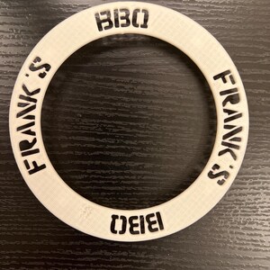 May include: White plastic ring with the words "Frank's" and "BIBO" printed in black on the outside of the ring.