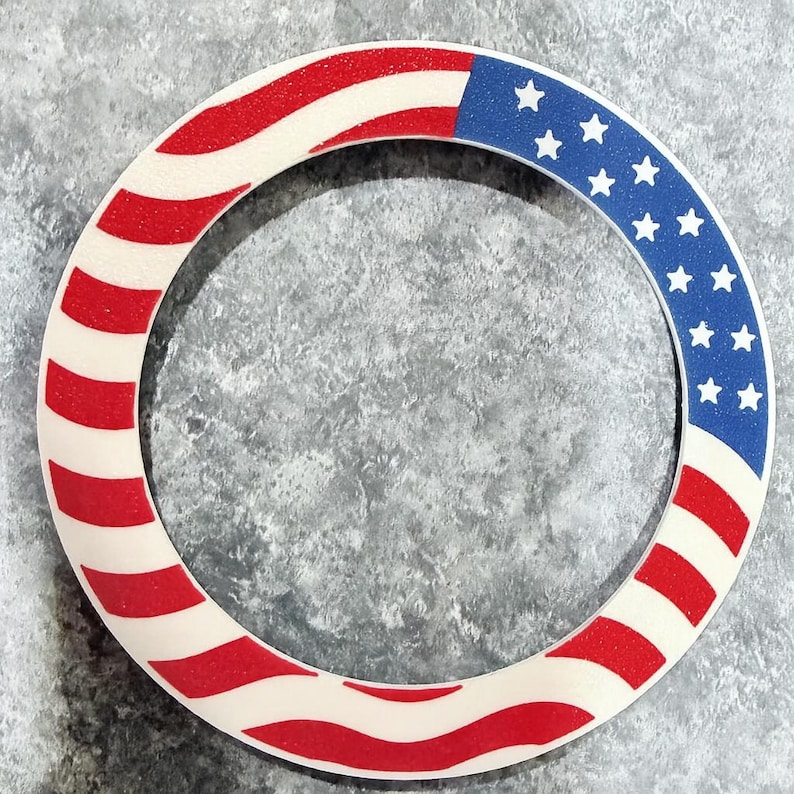 May include: Circular decorative item featuring the American flag design. The item has a white base with red stripes and a blue section with white stars. The design is reminiscent of the United States flag.