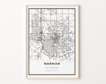 May include: A framed black and white map print of Norman, Oklahoma. The map features detailed street layouts and geographical features. The city name and coordinates are printed at the bottom. The frame is a light wood color.